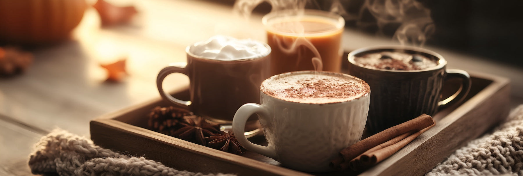 a wooden tray holding 4 fall drinks set on a wooden table and light notes of autumn decor around