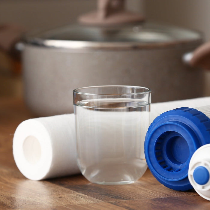 filters on their side next to a glass of water on a wood counter with a cooking put and dishes in the background