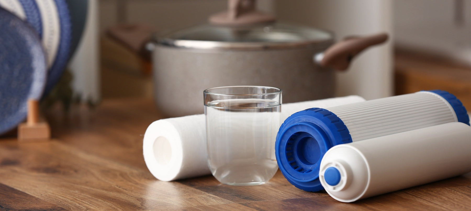 filters on their side next to a glass of water on a wood counter with a cooking put and dishes in the background